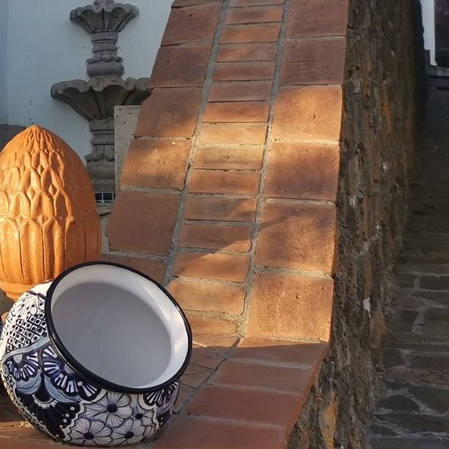 Pretil de ladrillo con una maceta de talavera y un remate de barro