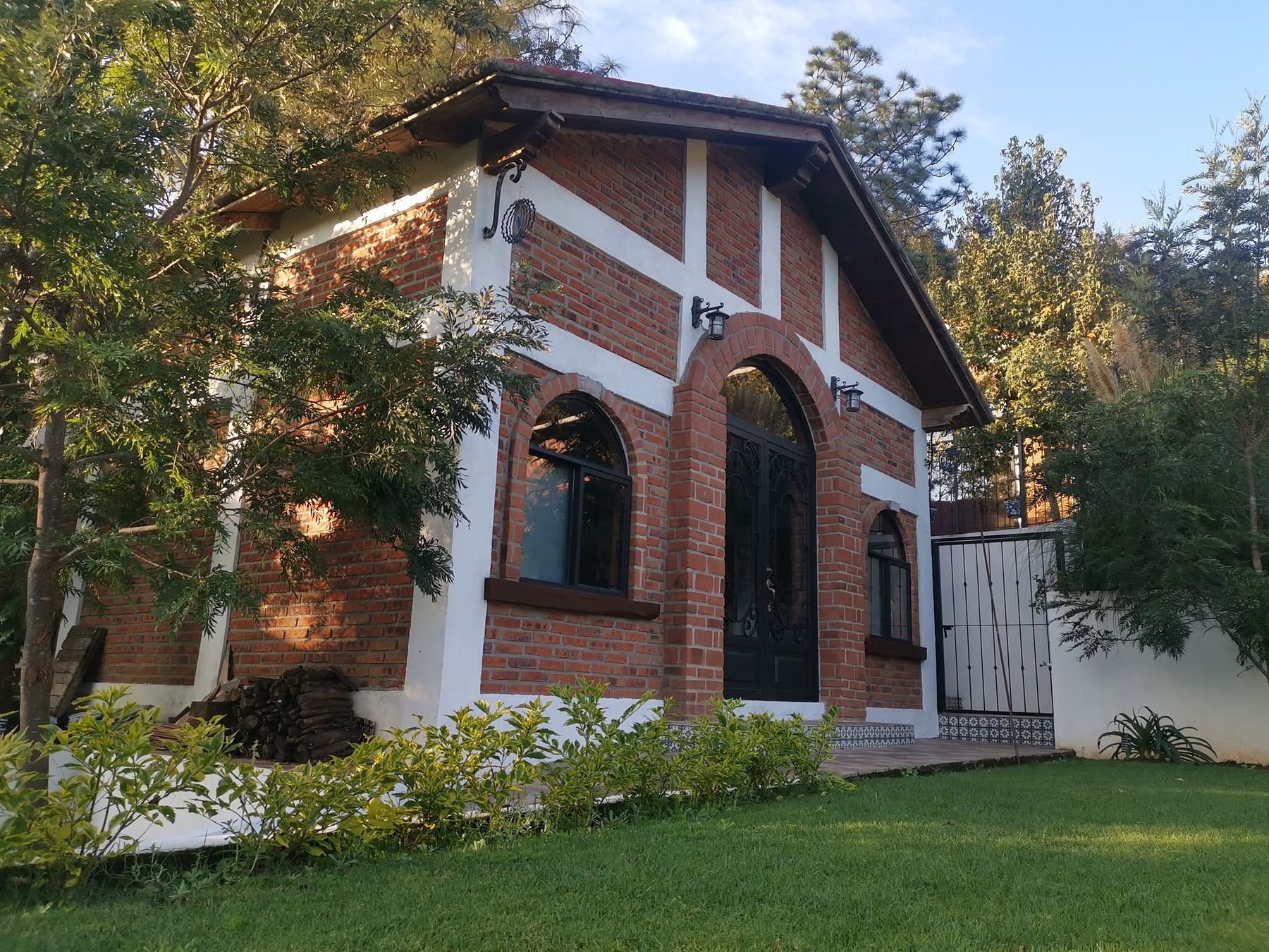 Salón de ladrillo con arcos de la finca en Los Fresnos, Charo, rodeado de jardín y pinos